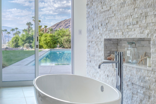 This bathroom has a chiseled quartz wall with a nook for toiletries.  Would you …